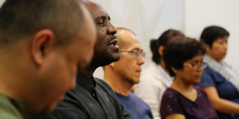 A group of diverse people participating in a devotional.